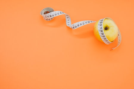 An apple with measuring tape isolated on orange background