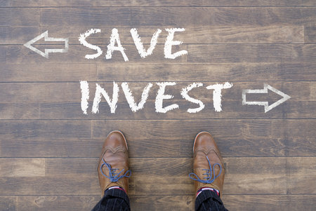 An overhead shot of a person standing in the middle of two decisions save or investの写真素材