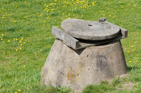 Stone sewer with cover on green grass.の写真素材