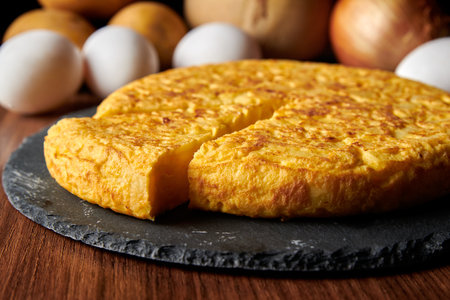 A closeup of a fresh tasty Spanish omelette and the ingredients on the background, a traditional dish from Spainの写真素材