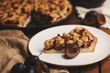 The delicious  Plum pie with coffee and ingredients with fabric on a wooden table with fabric backgroundの写真素材