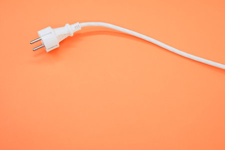A high angle shot of an electrical wire and plug on an orange surfaceの写真素材