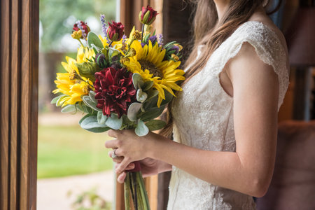 A shallow focus shot of the bride holding a beautiful bouquet with sunflowersの写真素材