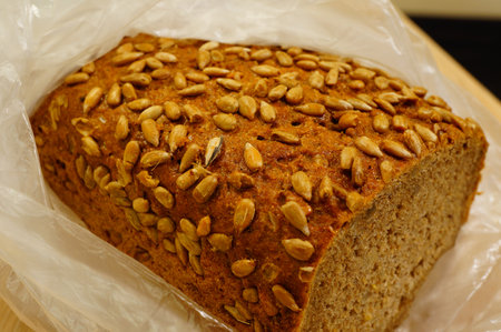 A closeup shot of a freshly baked handmade bread with sunflowers seeds in a plastic bag