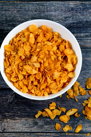 A top view of cornflakes in a bowl on a wooden table
