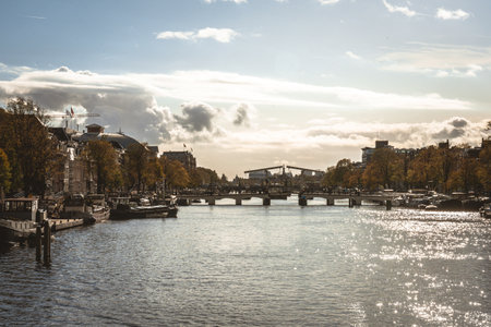 A river with boats in the city with the reflection of sunlight in itの写真素材