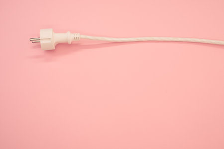 A high angle shot of an electrical wire and plug on a pink surfaceの写真素材