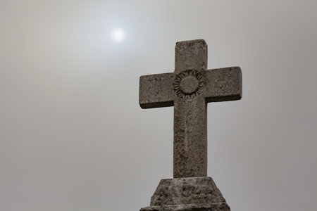 A statue of a stone cross in the graveyard with the sky in the background in New Orleansの写真素材