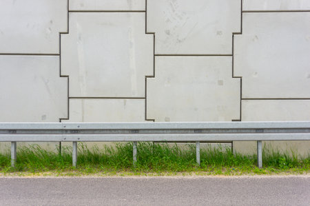 The street barrier the textured wall and the green grass