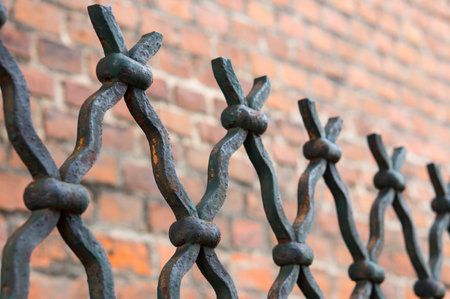 A closeup shot of the black metal fence in front of a brick wallの写真素材