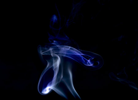 A closeup shot of blue smoke swirls against a black backgroundの写真素材