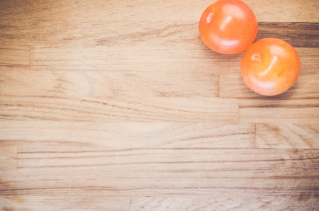 A top view of two orange plums on a wooden surface with a blank space for a textの写真素材