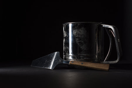 A closeup shot of a metal mug and a kitchen spatulaの写真素材