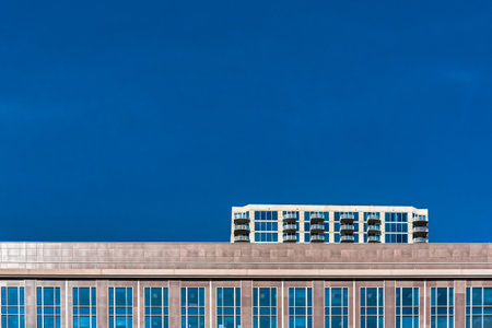 A low angle shot of tall glass and brick buildings under a clear blue skyの写真素材
