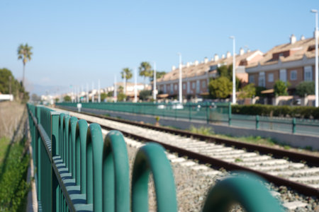 A green metal fence near the rails in the railway stationの写真素材