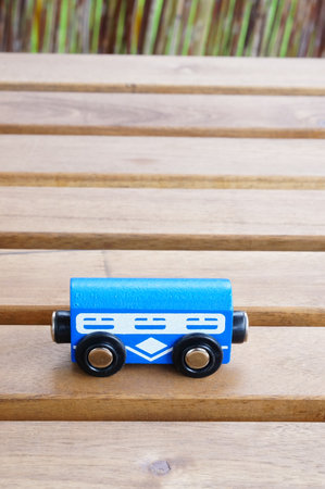 A vertical closeup shot of a blue toy car on a wooden surface