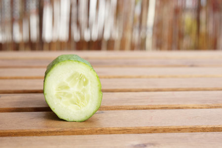 A closeup shot of a fresh piece of cucumber on a wooden surfaceの写真素材