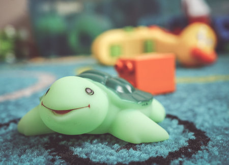 A beautiful shot of a green smiling turtle toy on the blue carpet in the roomの写真素材