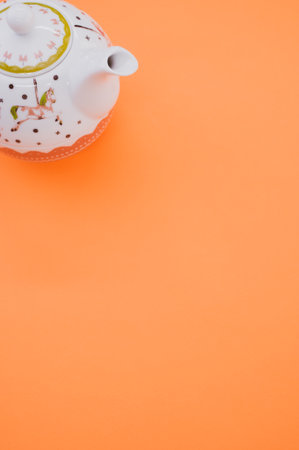 A vertical shot of decorative teapot isolated on an orange backgroundの写真素材