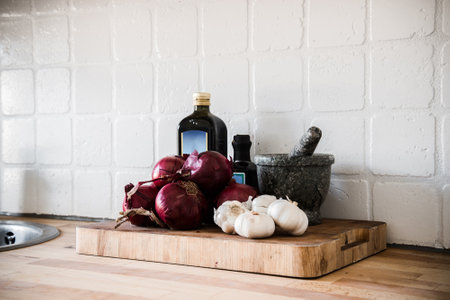 red onion, garlic and pestle on cutting boardの写真素材