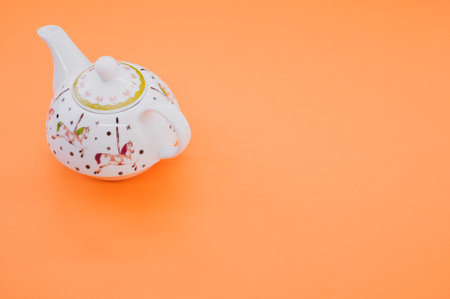 A top view of decorative teapot isolated on an orange background