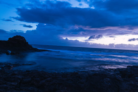 The dark cloudy sunset sky over the shore of the oceanの写真素材