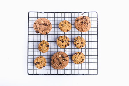 A high angle shot of freshly baked homemade chocolate chip cookies on an oven net on a white...
