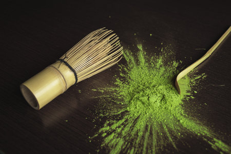 A closeup shot of a cooking brush next to poured green powder and a wooden spoon