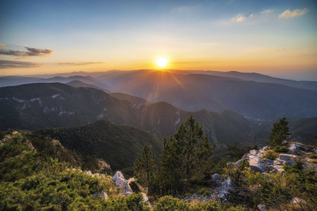 A beautiful shot of the long distant valley and a sun going behind the mountains during sunset