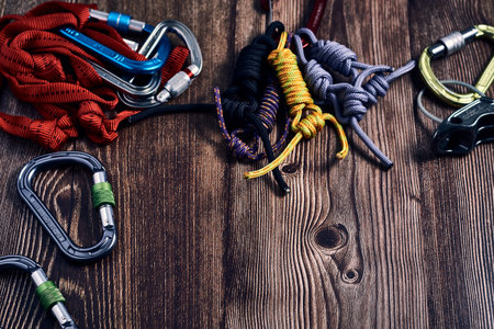 A closeup shot of many colorful climbing carabiners and knots on a wooden surfaceの写真素材