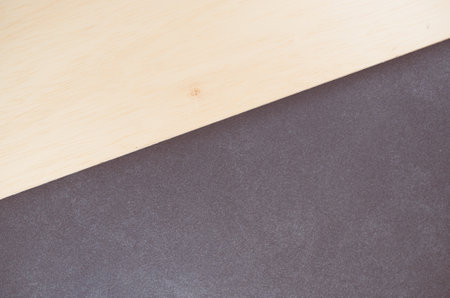 A top view closeup of a grey surface next to a wooden plank