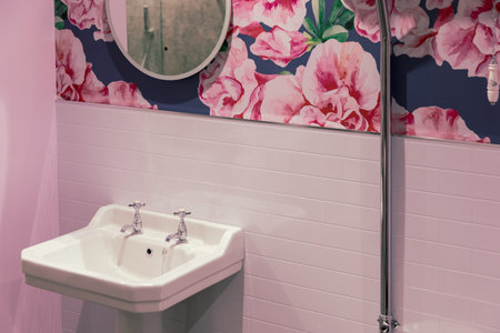 The inside of a bathroom with a sink and a mirror with a pink interior and floral designの写真素材
