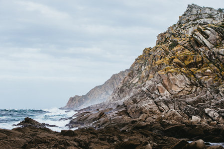 A closeup of rocks surrounded by the sea under a cloudy sky at daytimeの写真素材