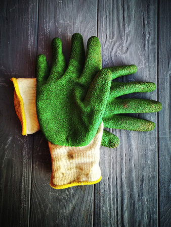 A vertical closeup of dirty green gloves on a wooden backgroundの写真素材