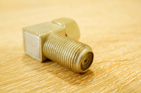 A closeup shot of a steel metallic adapter on a wooden table