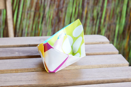 A closeup shot of a colorful handmade paper boat on a wooden table
