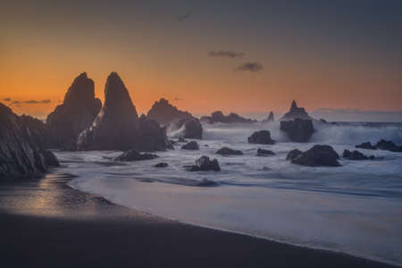 The rock formations in the foamy water of the sea at sunset
