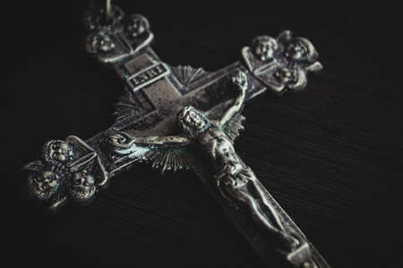 A closeup shot of a metal cross on a wooden black tableの写真素材