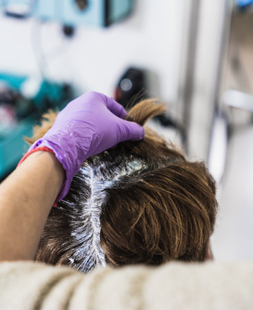 A vertical closeup shot of a hairdresser dying a woman's short hair in a beauty salon