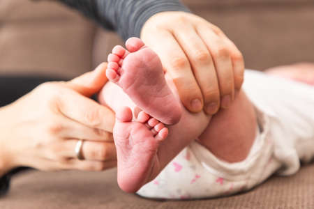 A closeup of a person playing with a newborn child's feet lying on a bed