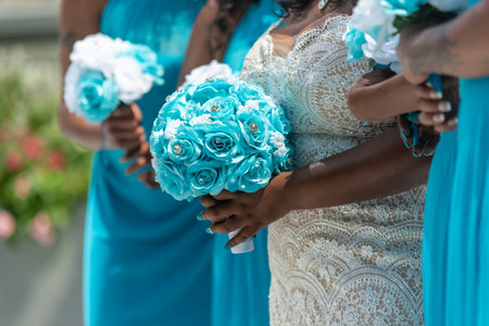 A closeup shot of the bride and three of her bridesmaids standing and holding bouquets, no faces capturedの写真素材
