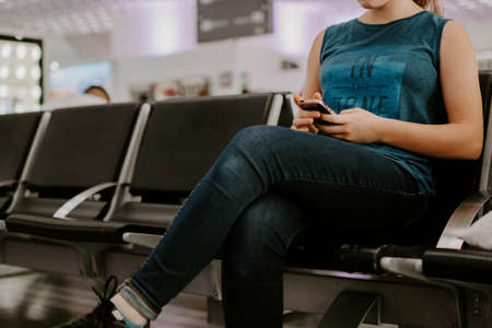 A closeup shot of a lady using her phone while waiting in a stationの写真素材