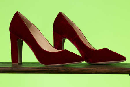 A closeup shot of a pair of beautiful ladies shoes with the large heel isolated on green backgroundの写真素材