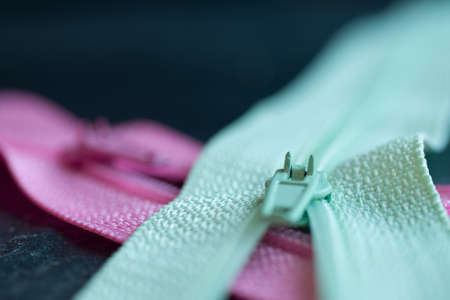 A closeup shot of pink and green zippers on a blurred backgroundの写真素材