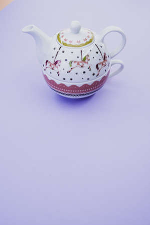 A vertical shot of decorative teapot with cup isolated on purple backgroundの写真素材