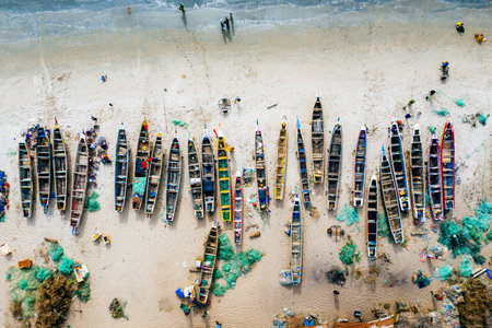 An overhead aerial shot of different colored boats on a sandy beach with the sea nearbyの写真素材