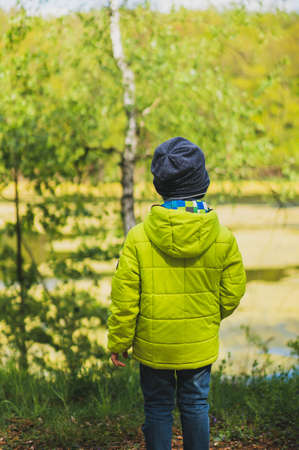 A vertical shot of a kid with a yellow coat playing in the playground with a blurred backgroundの写真素材