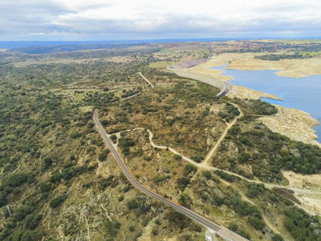 An aerial shot of a road in the middle of trees under a cloudy sky in Salamanca, Spainの写真素材
