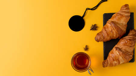 A top view of croissant bread with star anise tea isolated on yellow backgroundの写真素材