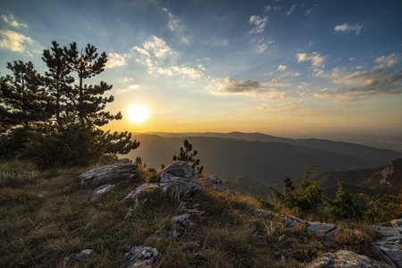 A beautiful shot of the long distant valley and a sun going behind the mountains during sunsetの写真素材